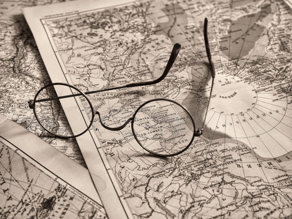 Round eyeglasses rest on an antique world map, evoking a sense of exploration.